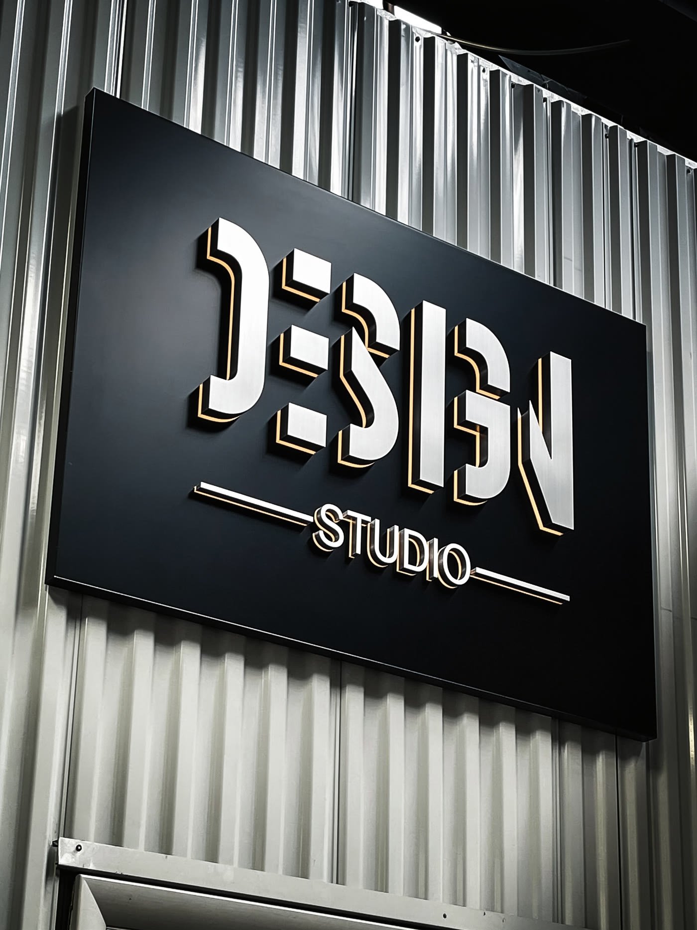 Brushed metal dimensional letters on a black panel